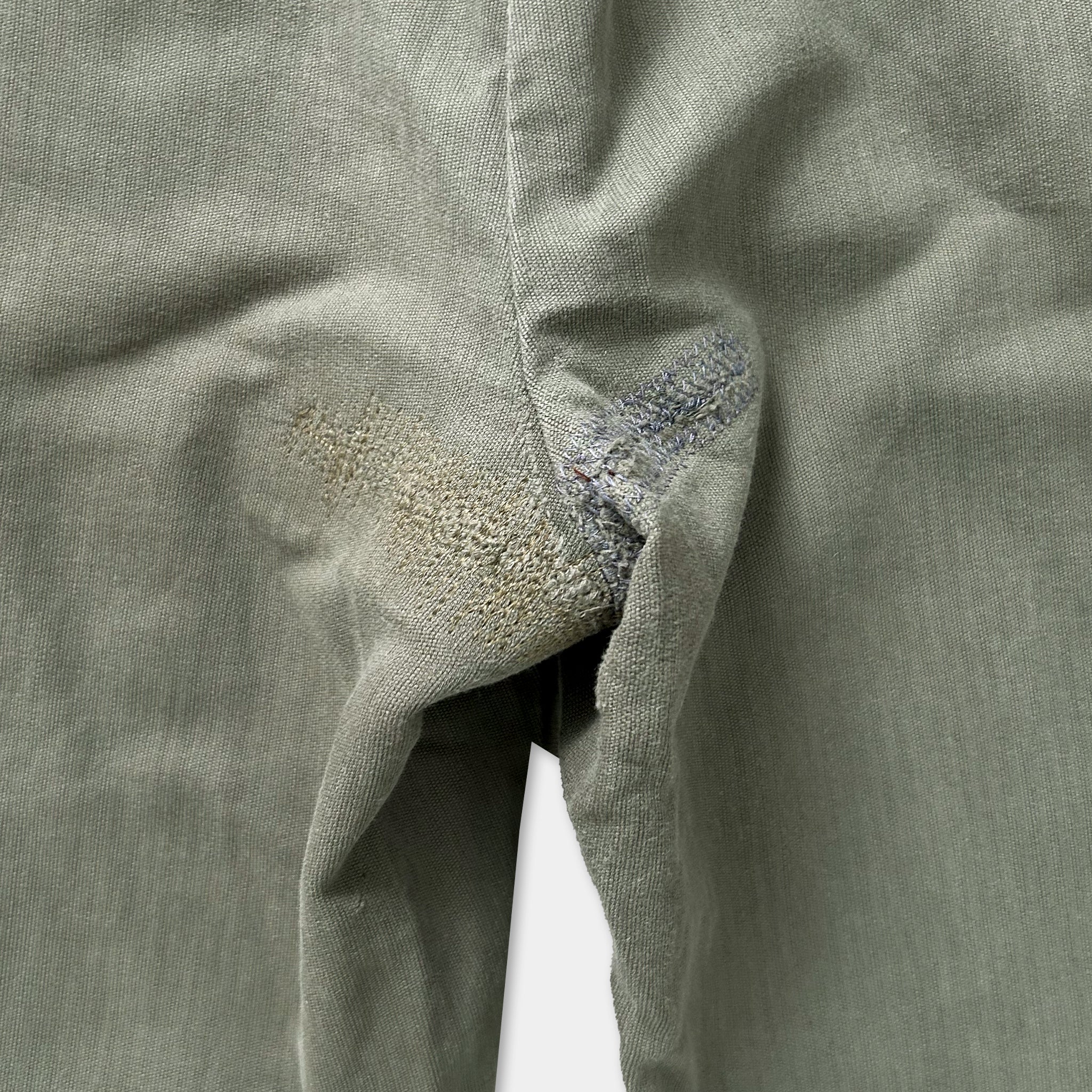 a close-up view of a pair of gray pants with a noticeable tear or rip in the fabric.