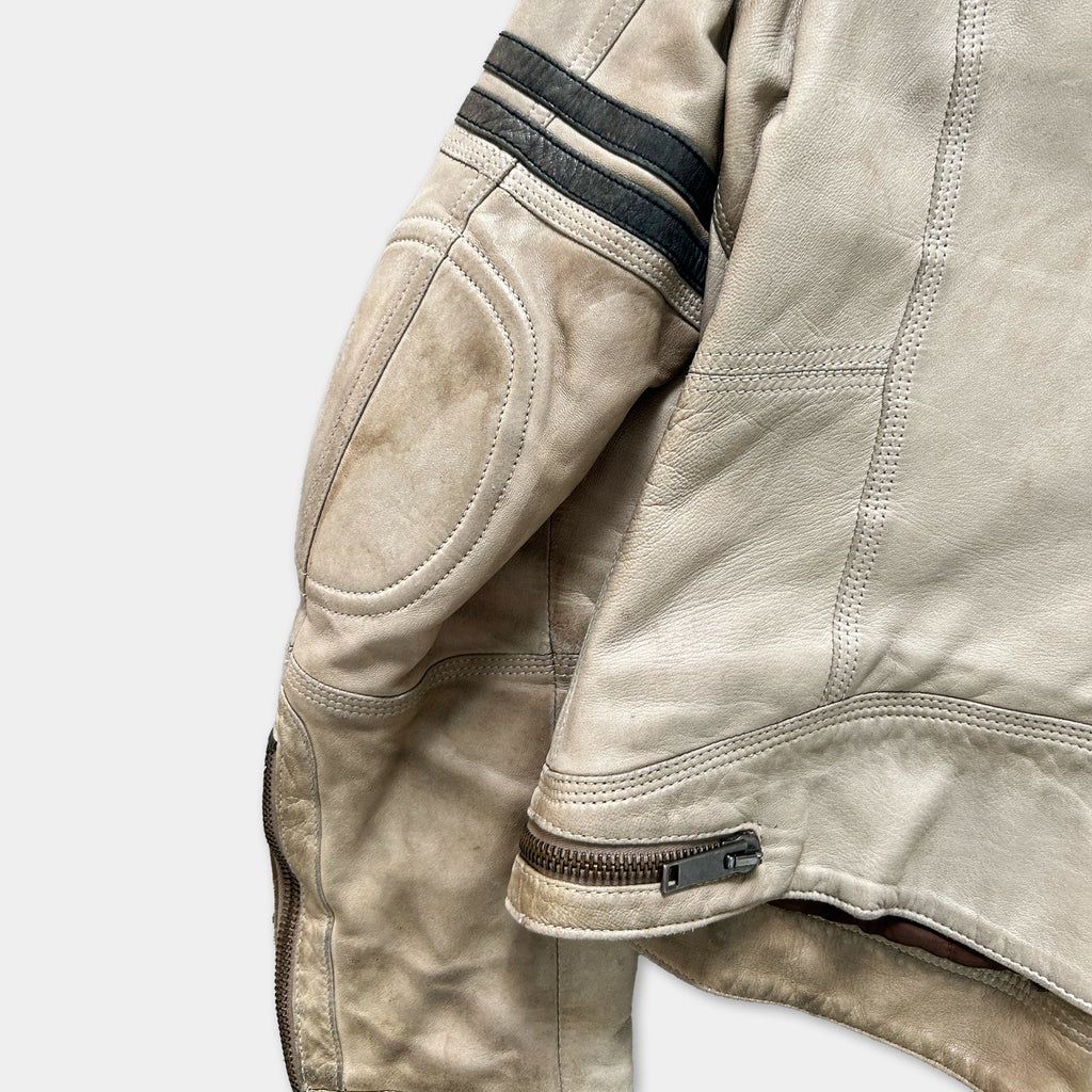 A close-up view of a tan leather jacket with black stripes on the sleeves and zipper.