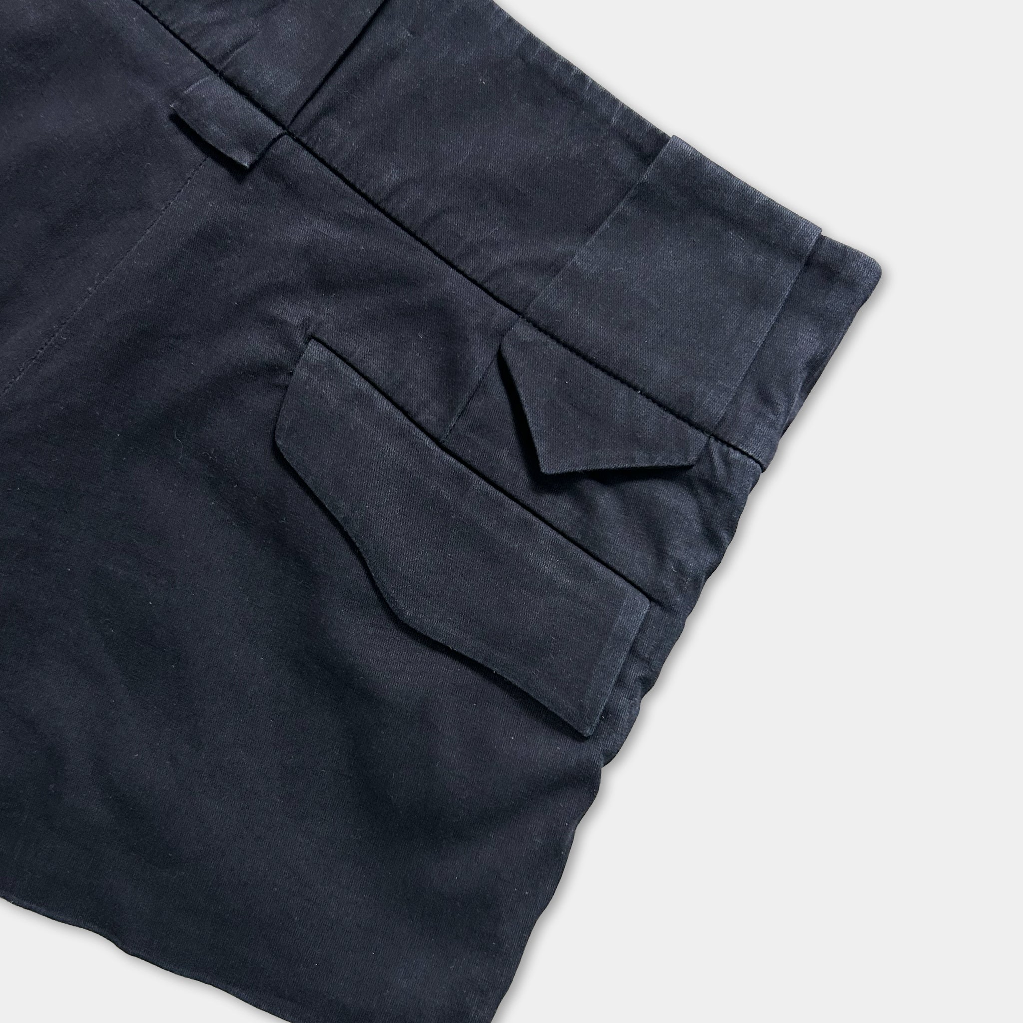 A close-up view of a pair of dark blue pants with a pocket and a belt loop.