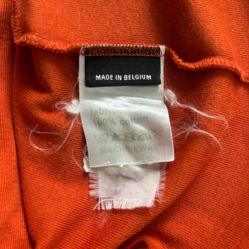a close-up view of a red fabric, possibly a shirt or garment, with a label attached to it. The label appears to be a tag or label indicating the material and manufacturing origin.