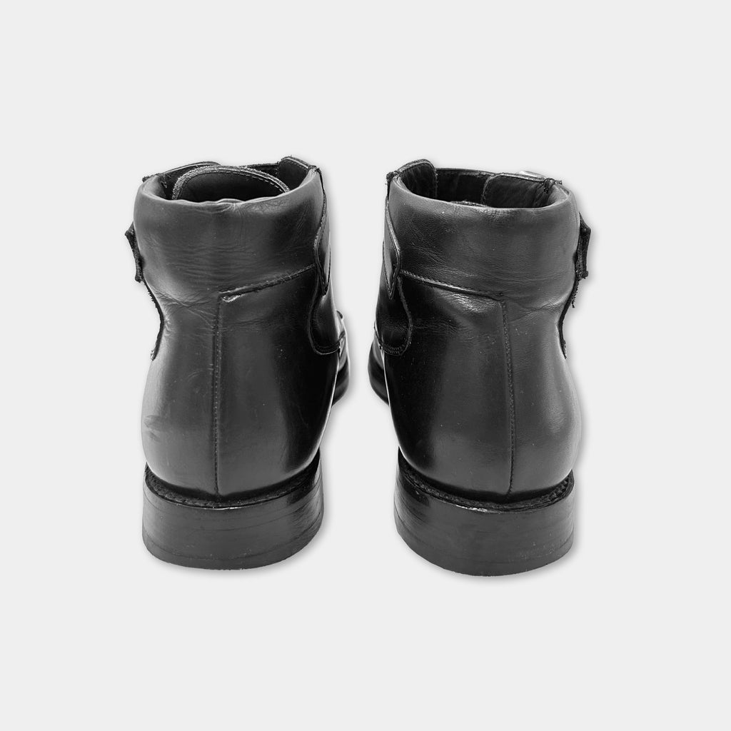 A pair of black leather boots with a pointed toe and a low heel, facing away from the camera.