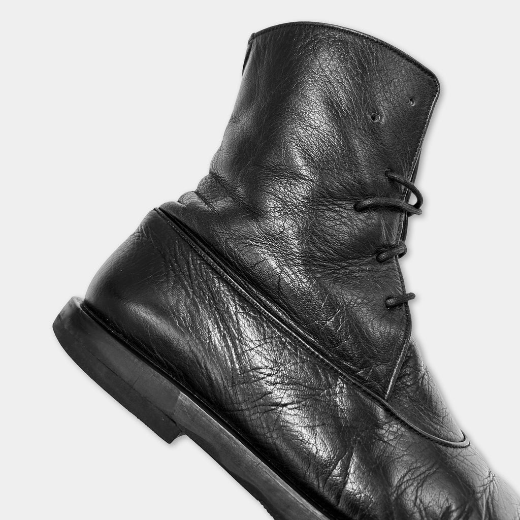 A close-up view of a black leather boot with a lace-up design.