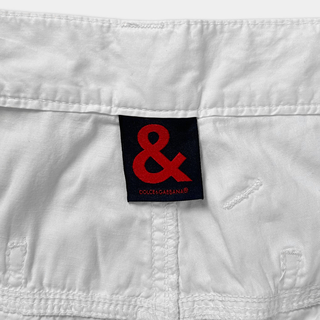 A close-up view of a white fabric, possibly denim or a similar material, with a red and black label featuring the '&' logo prominently displayed.