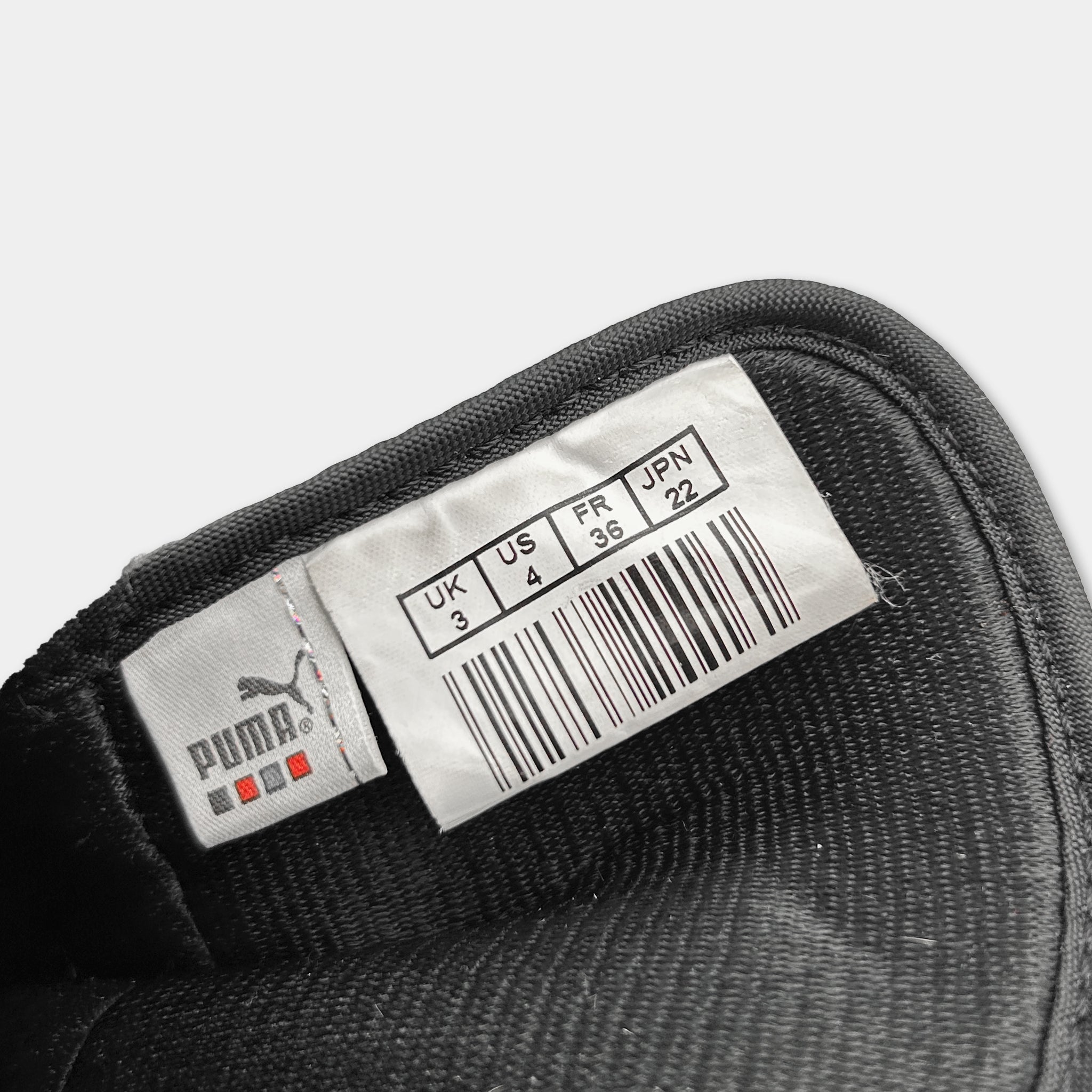 A close-up view of a black shoe label with a barcode and text indicating the shoe size and country of origin.