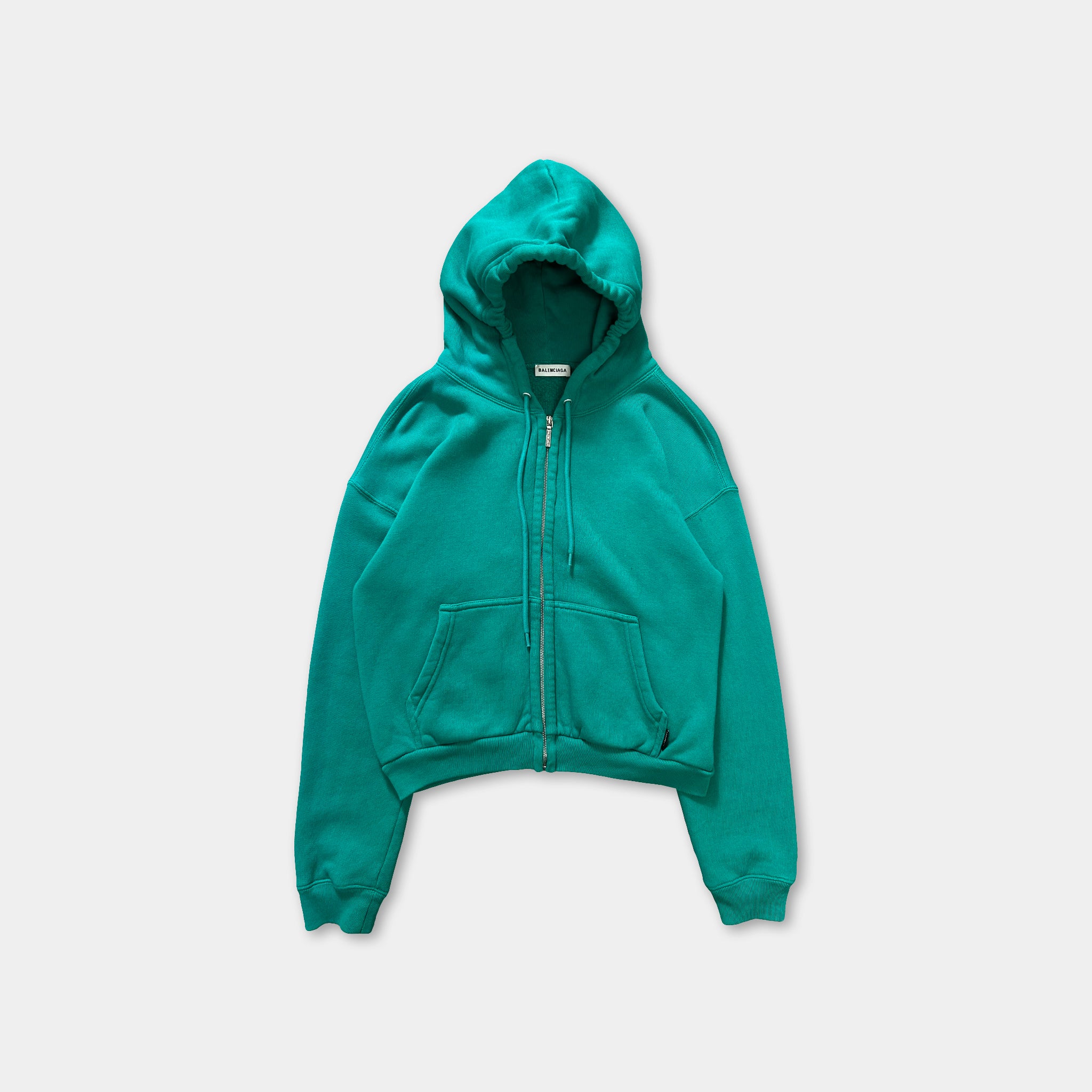A turquoise zip-up hoodie with a drawstring hood is shown against a white background.