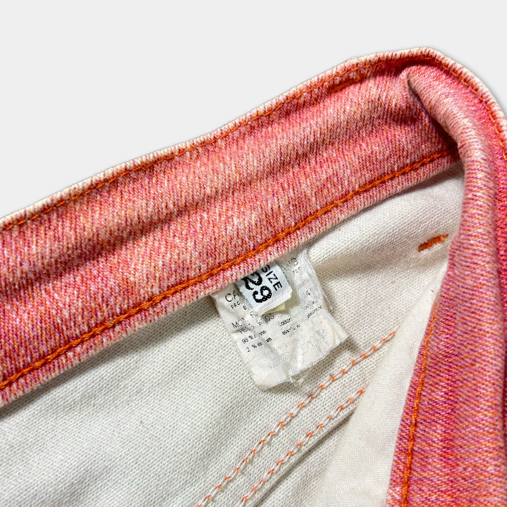 A close-up view of a pair of red and white jeans, showing the label and zipper.