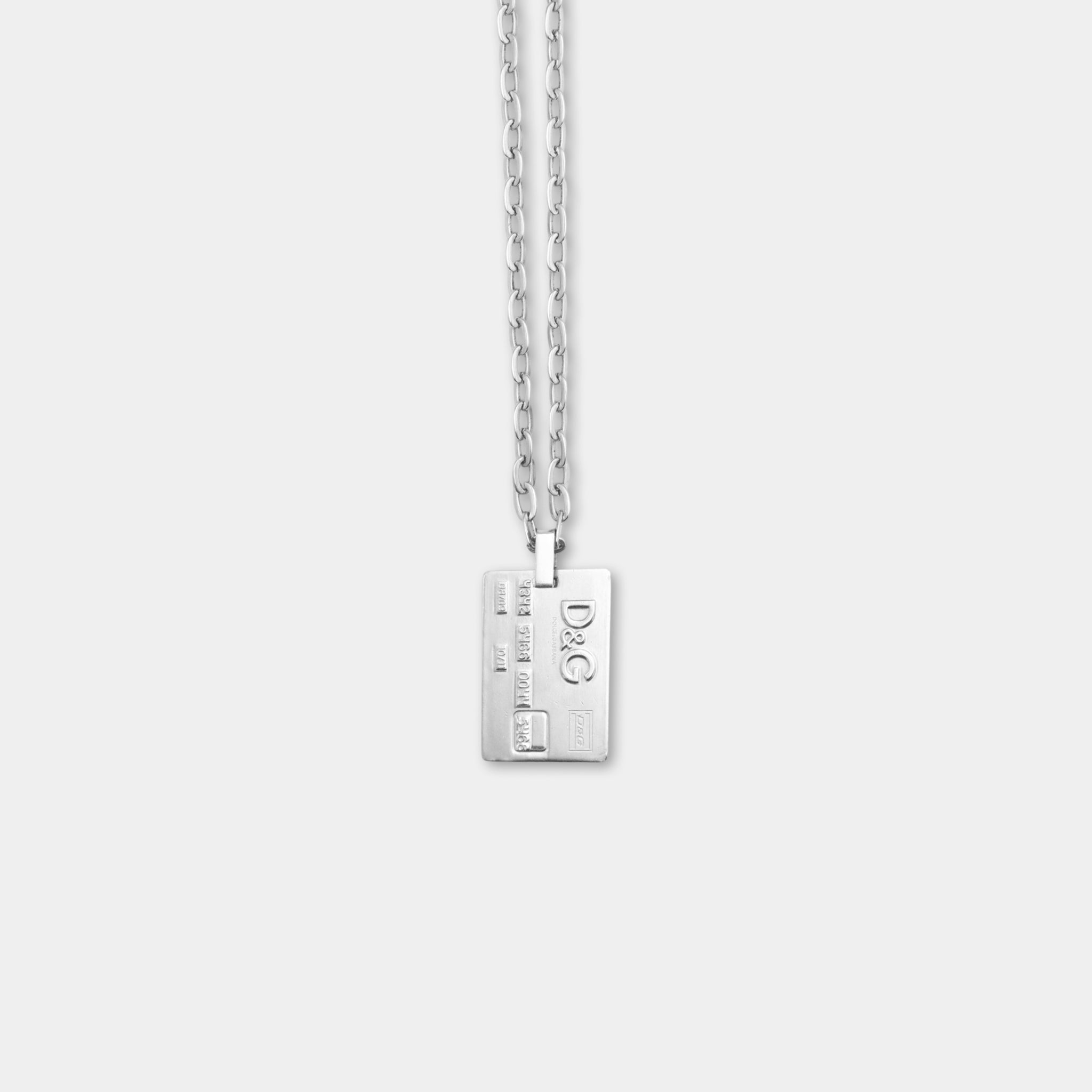 A silver necklace with a rectangular pendant featuring the letters 'D&G' on it.