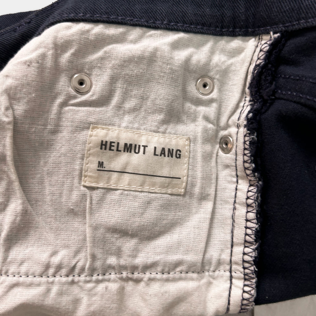 A close-up view of a fabric label on a pair of navy blue jeans, with the brand name "Helmut Lang" printed on it.