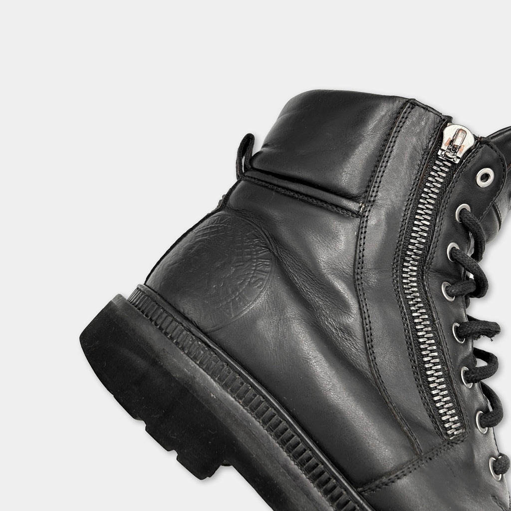 A close-up view of a black leather boot with a zipper detail and a sole visible.