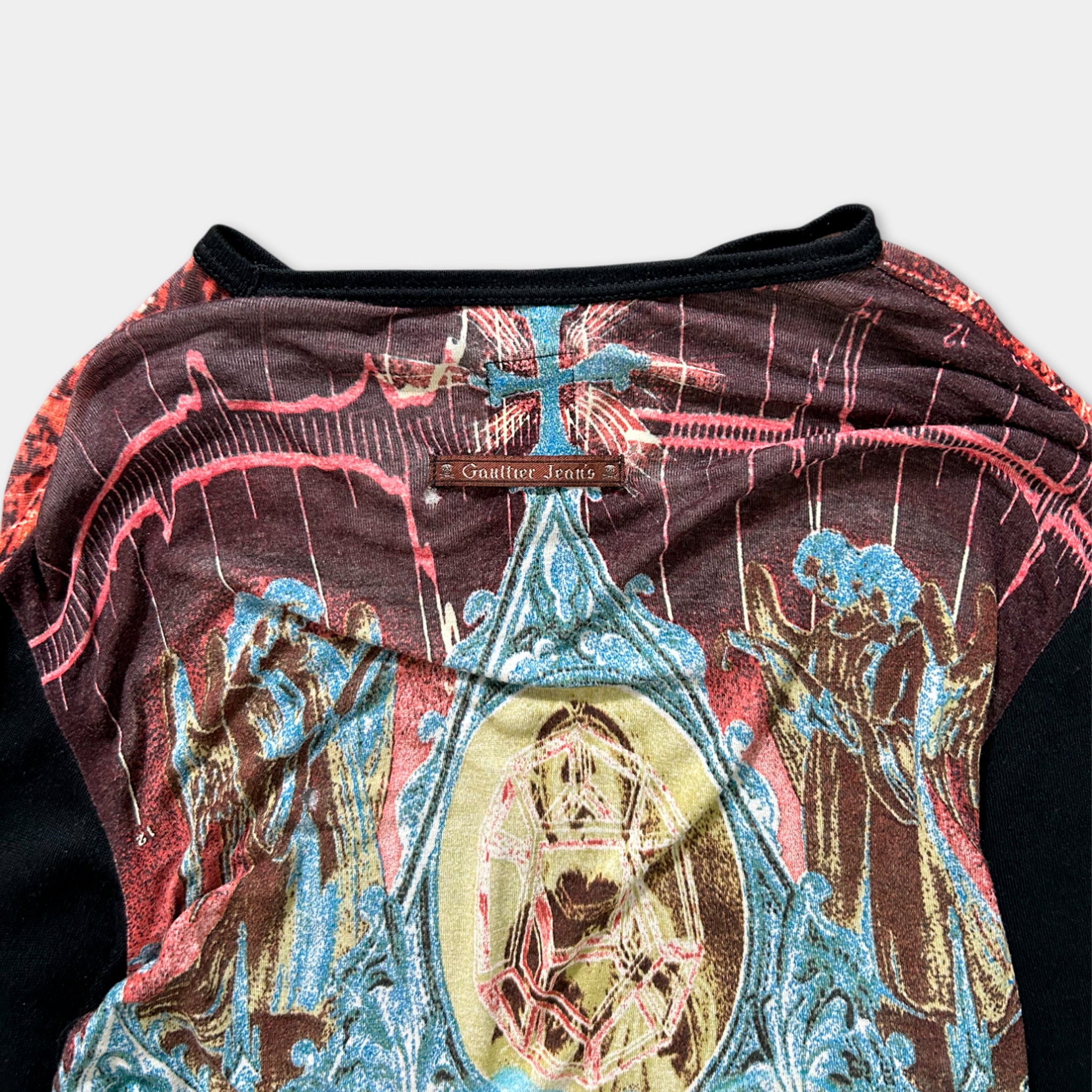a colorful, patterned shirt with a religious design featuring a cross and various figures.