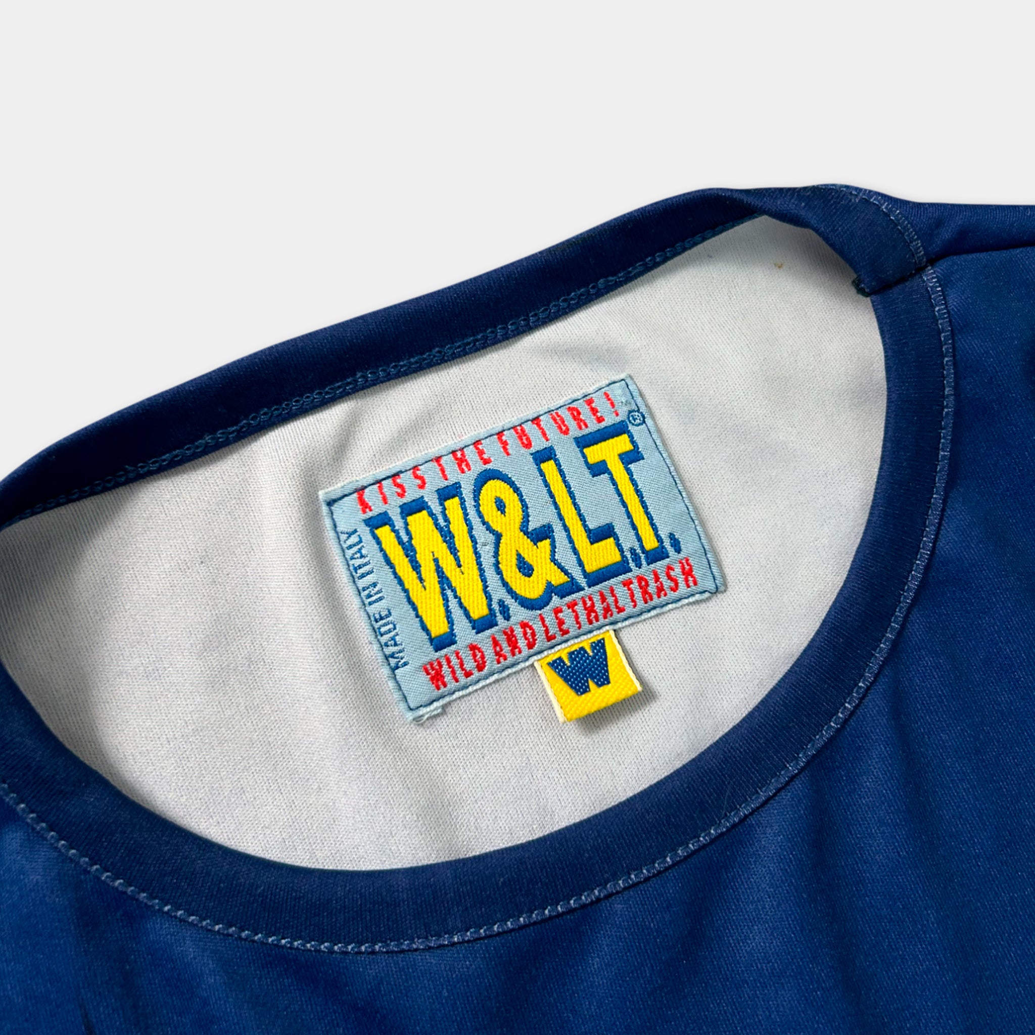 A close-up view of a blue t-shirt with a label on the collar.