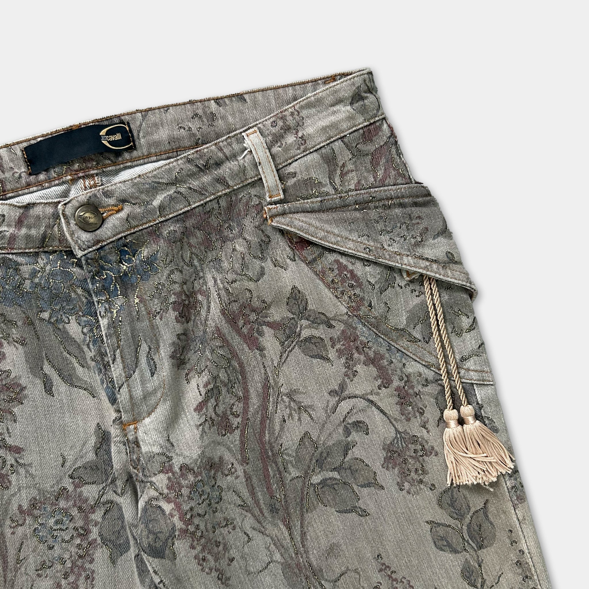 A pair of gray floral patterned jeans with a tassel hanging from the waistband.