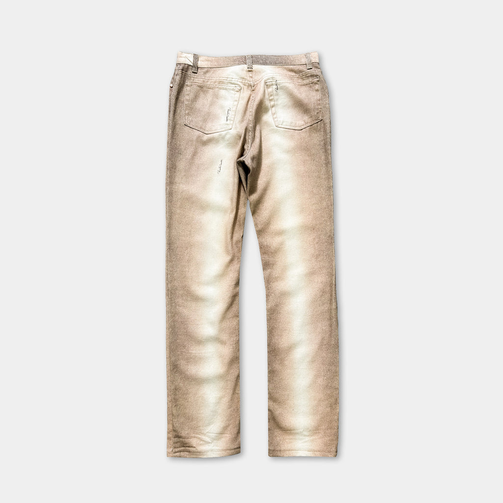 A pair of tan-colored jeans with visible wear and tear, including a small tear in the pocket and frayed edges on the knees.