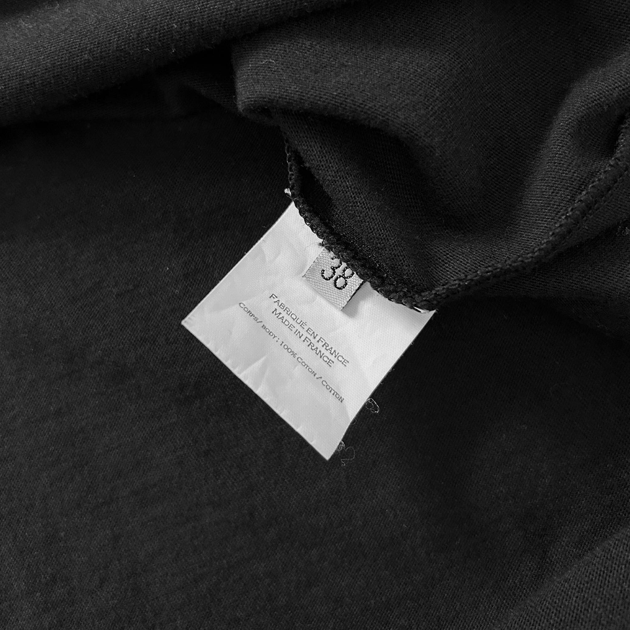 a close-up view of a black fabric, with a white label attached to it. The label appears to be a garment tag or label, possibly indicating the brand, size, or other information about the clothing item.