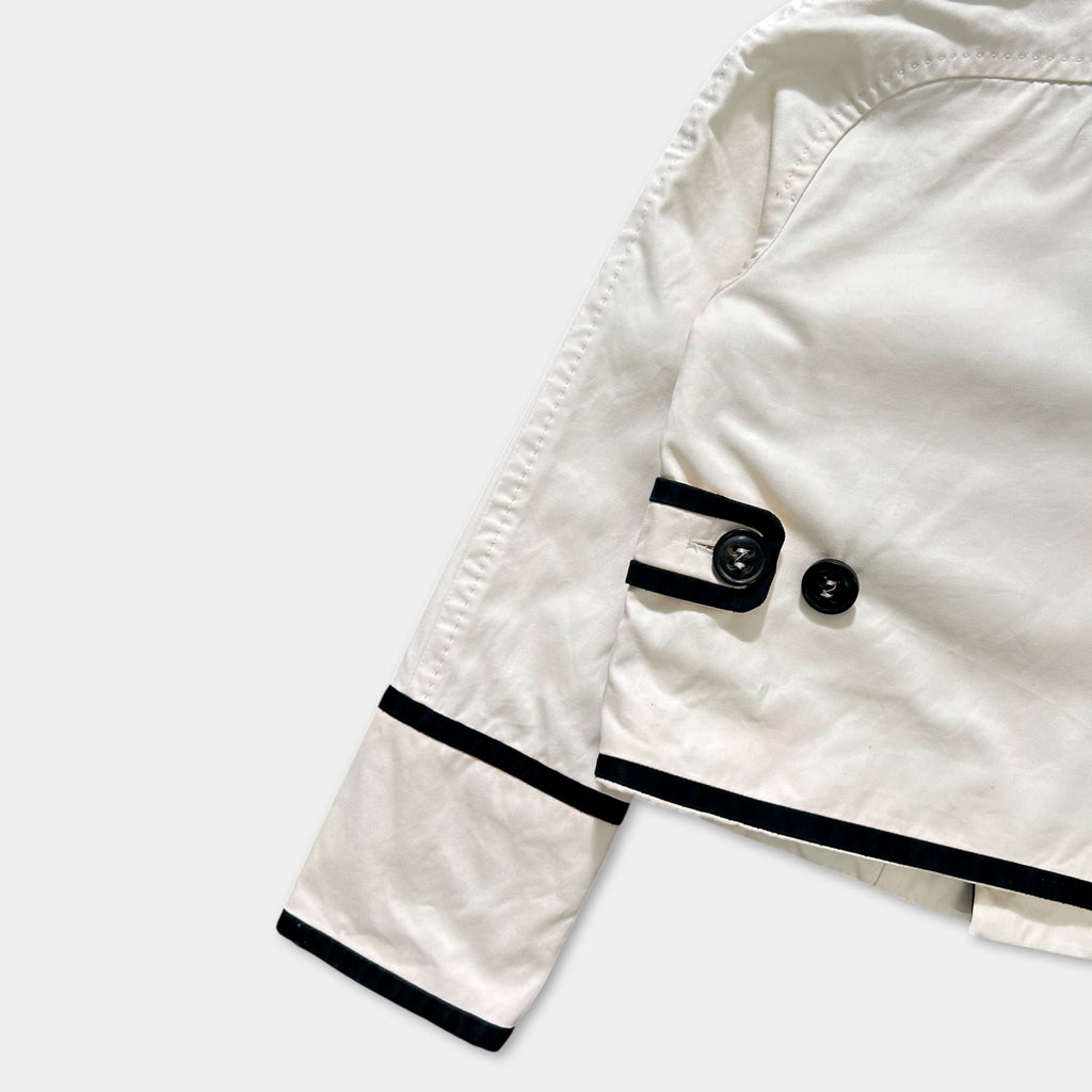 A white jacket with black trim and buttons is shown in the image.