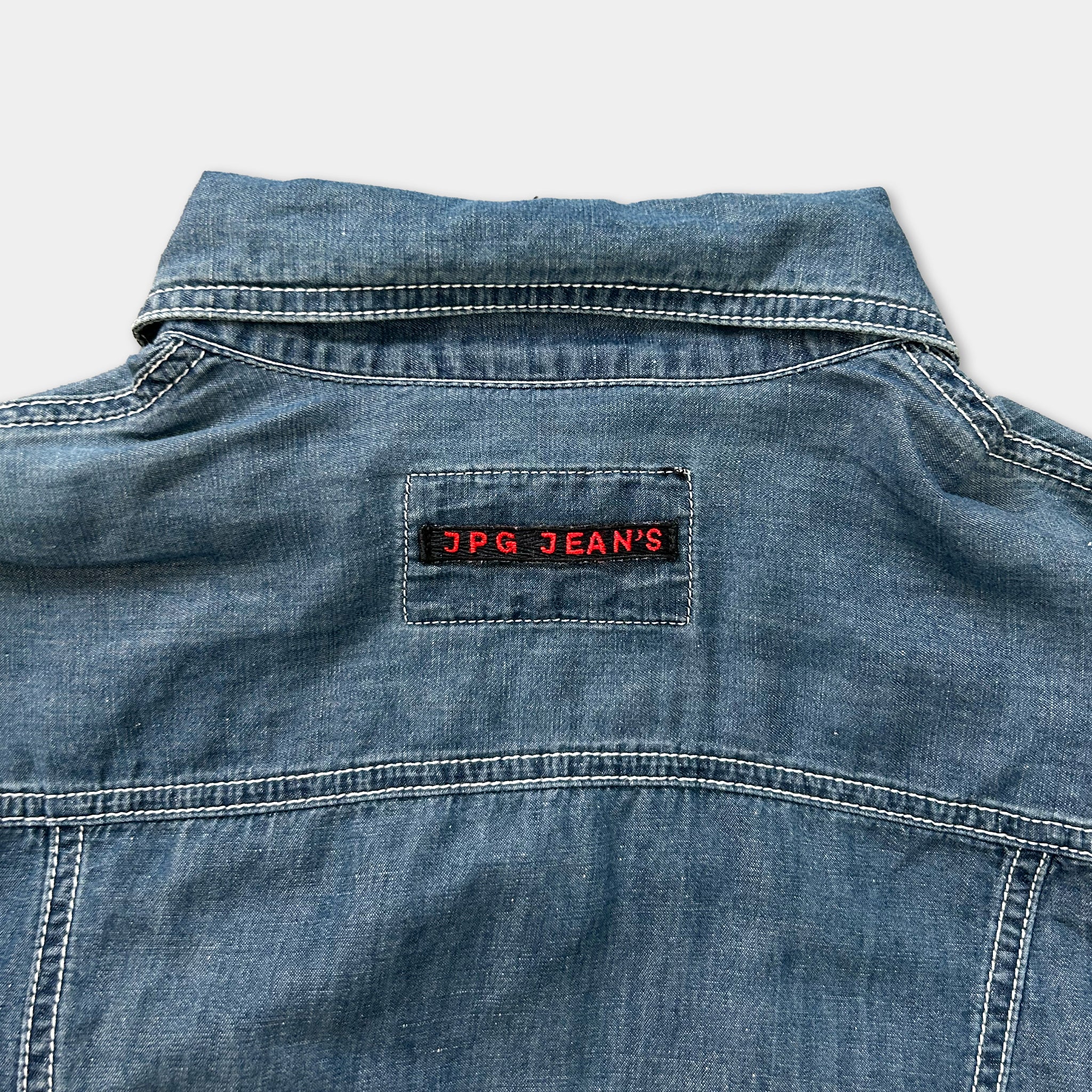 the back of a denim jacket with a red patch on the collar that says "JPG Jean's".