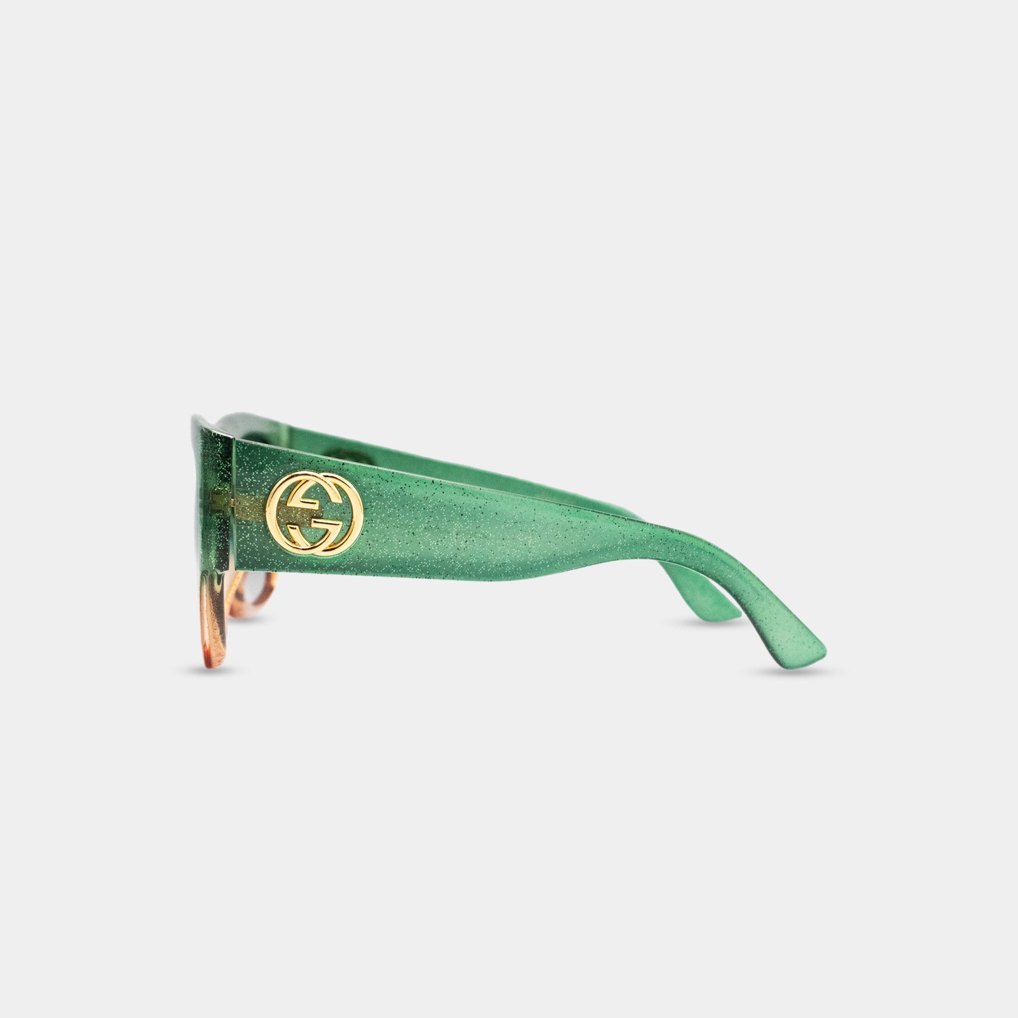 A pair of green Gucci sunglasses with a gold logo on the frame.