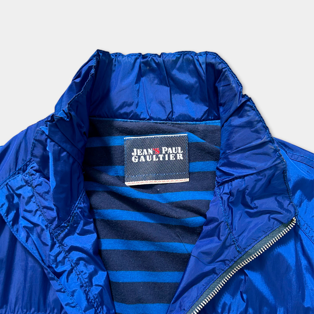 A close-up view of a blue jacket with a label that reads "Jean Paul Gaultier" on the collar.