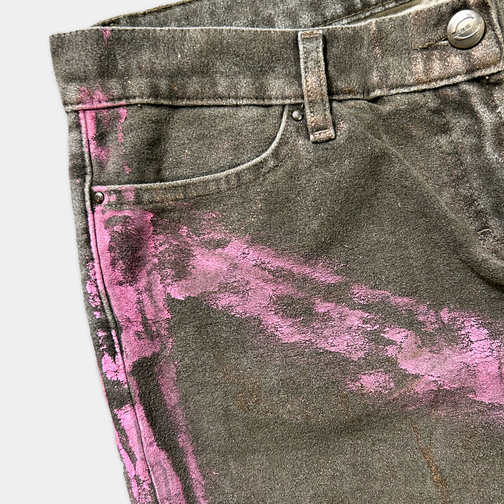 A close-up view of a pair of dark grey jeans with pink splatters on the fabric.