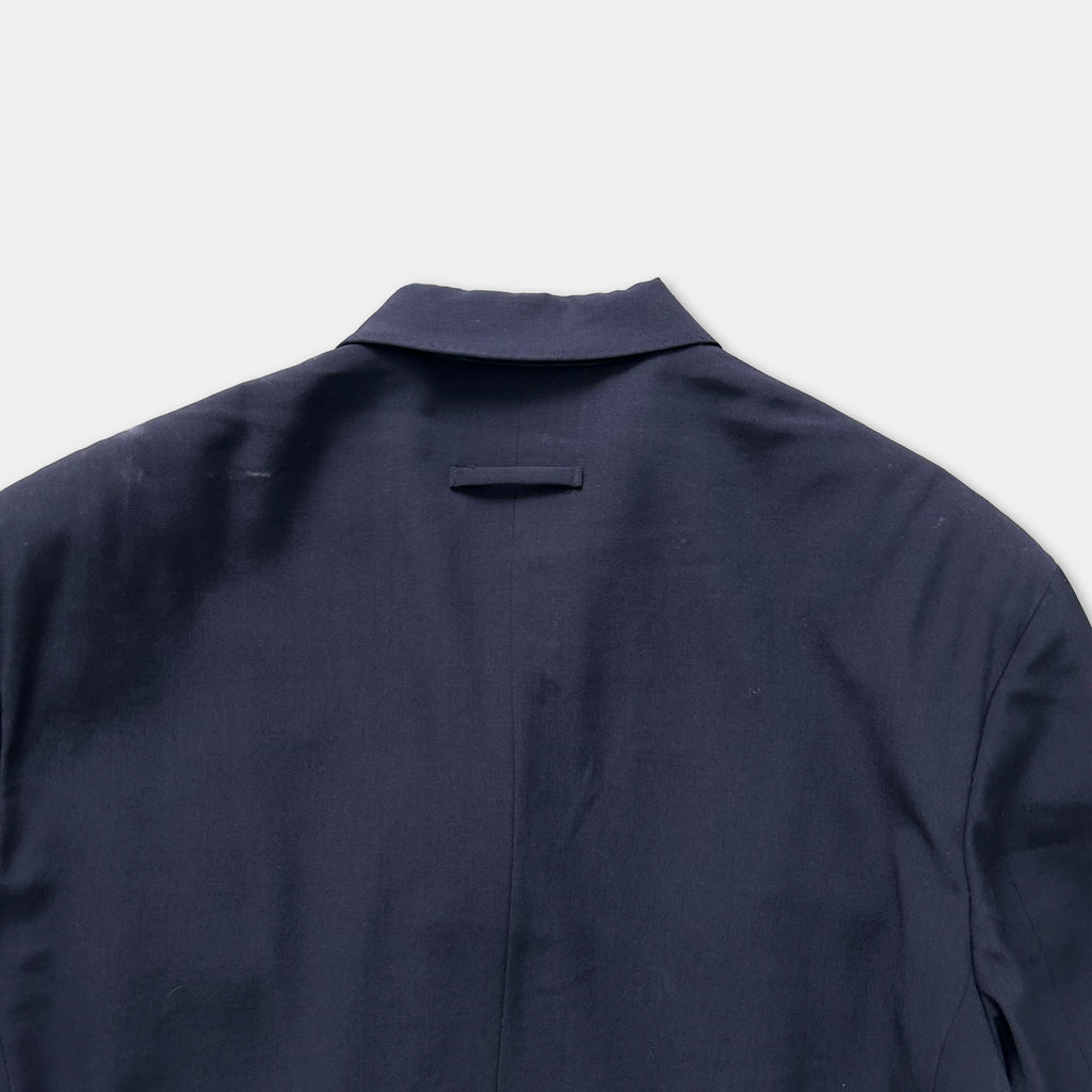 the back of a navy blue jacket or blazer, with a collar and a pocket visible.