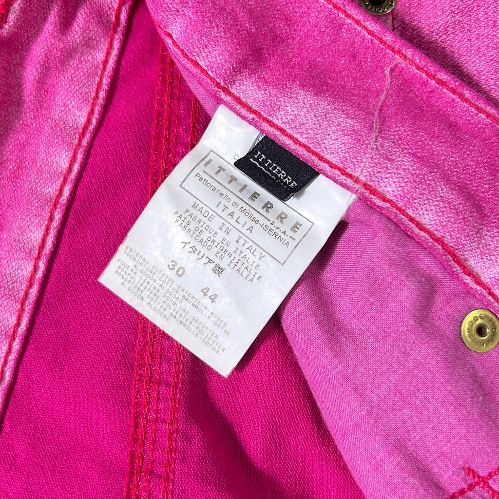 A close-up view of a pink fabric, possibly denim, with a label attached to it. The label appears to be a product label or tag, likely indicating the brand, material, and other relevant information about the fabric.