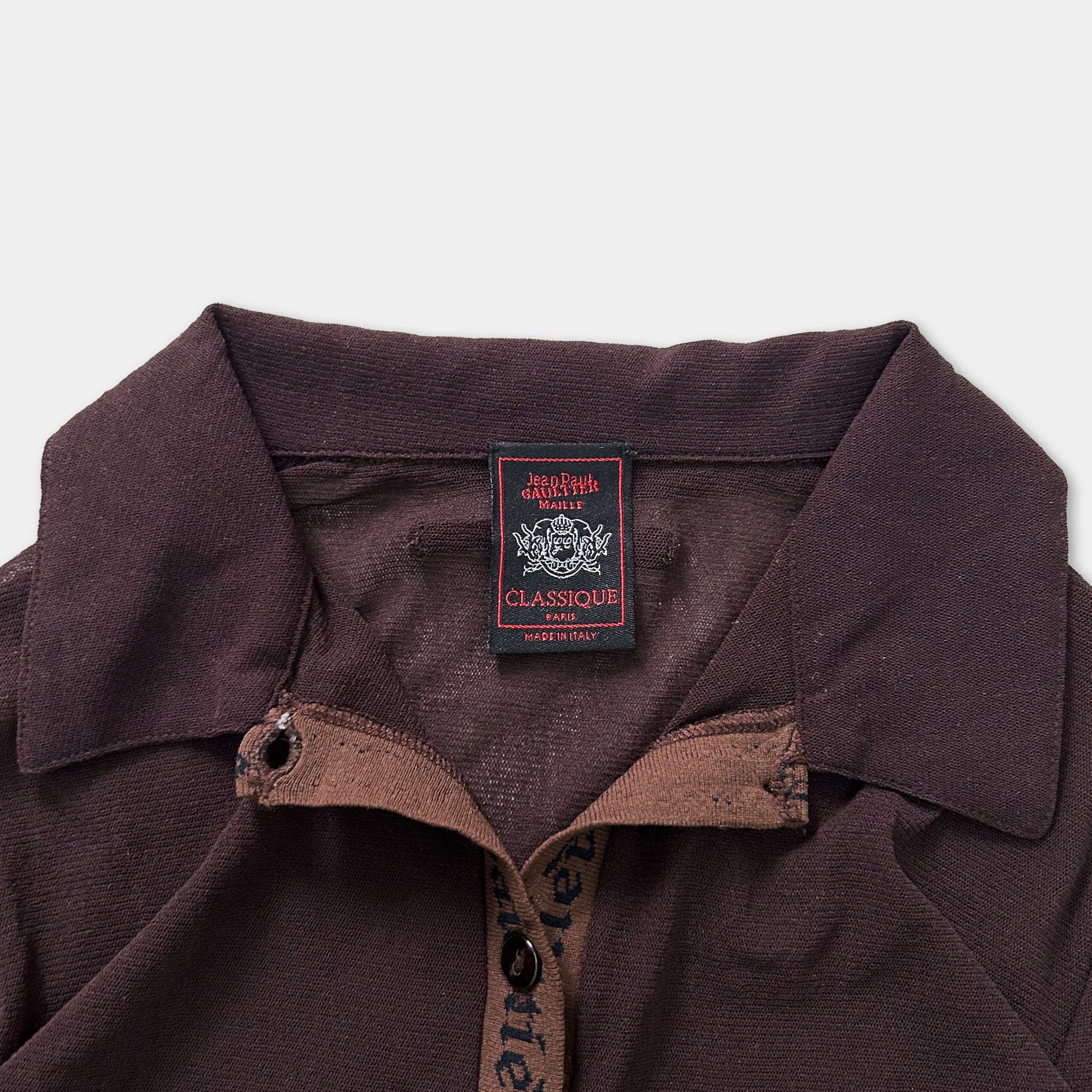 A close-up view of a brown collared shirt with a label on the collar.