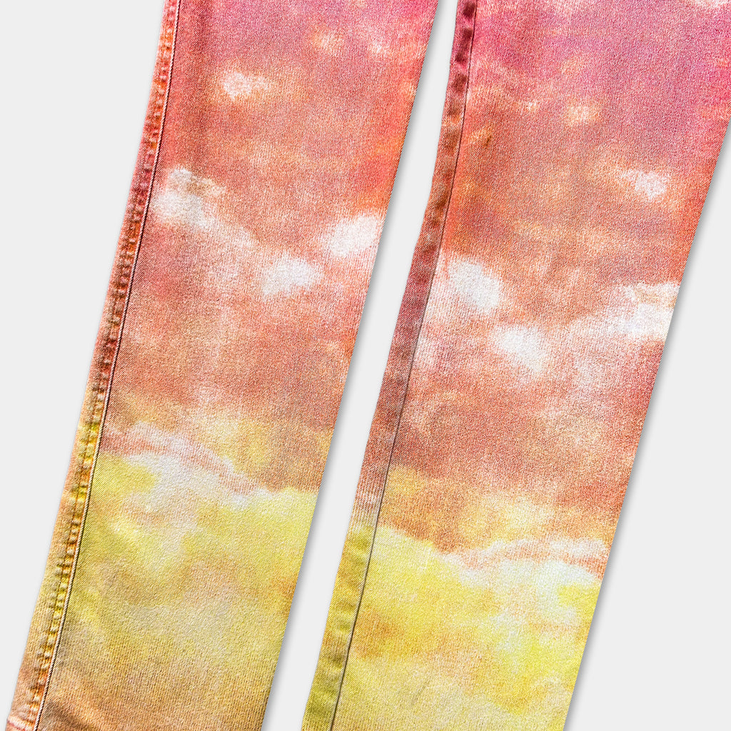 a pair of colorful jeans with a vibrant, gradient pattern of orange and yellow. The jeans appear to be made of denim fabric and are positioned side by side, with the left leg slightly overlapping the right leg.