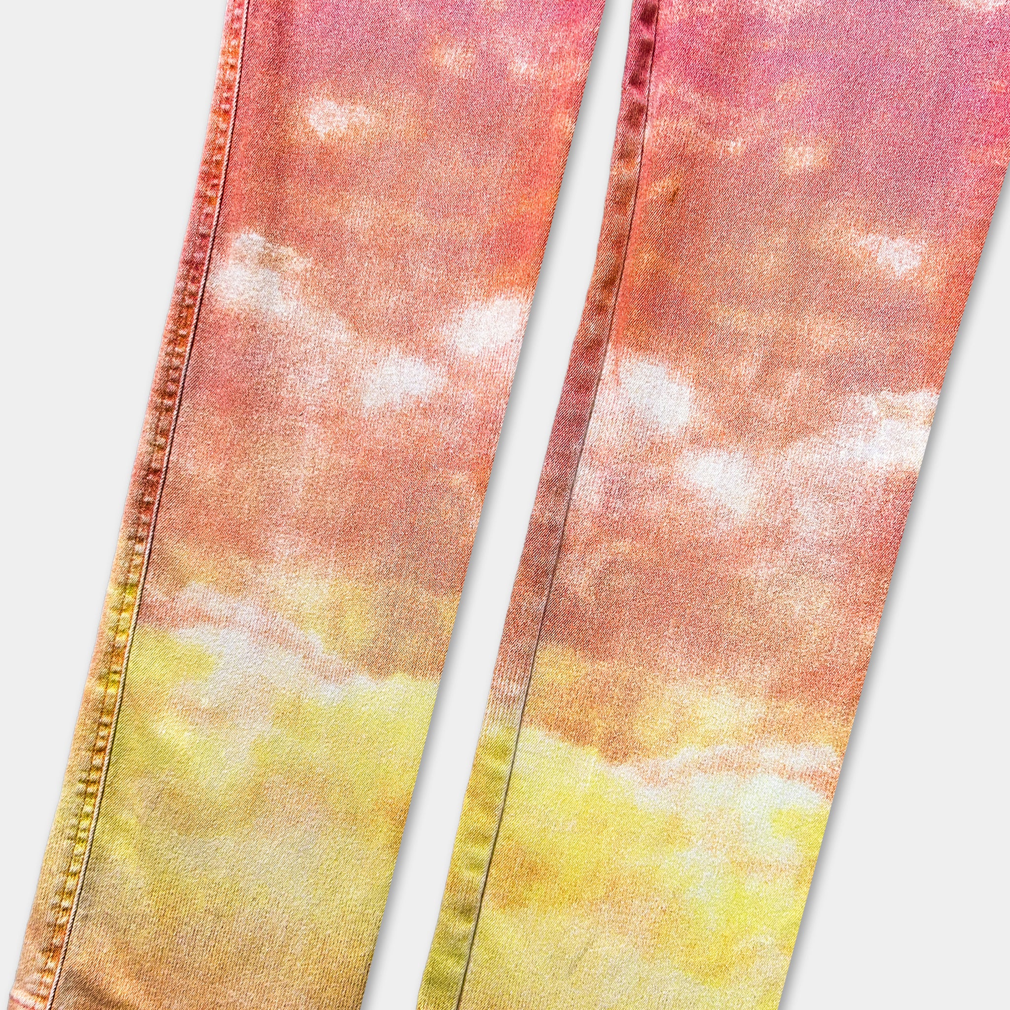 a pair of colorful jeans with a vibrant, gradient pattern of orange and yellow. The jeans appear to be made of denim fabric and are positioned side by side, with the left leg slightly overlapping the right leg.