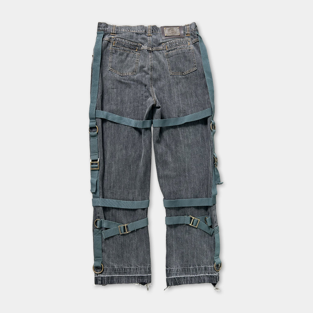 A pair of gray jeans with multiple straps and buckles attached to the waistband.