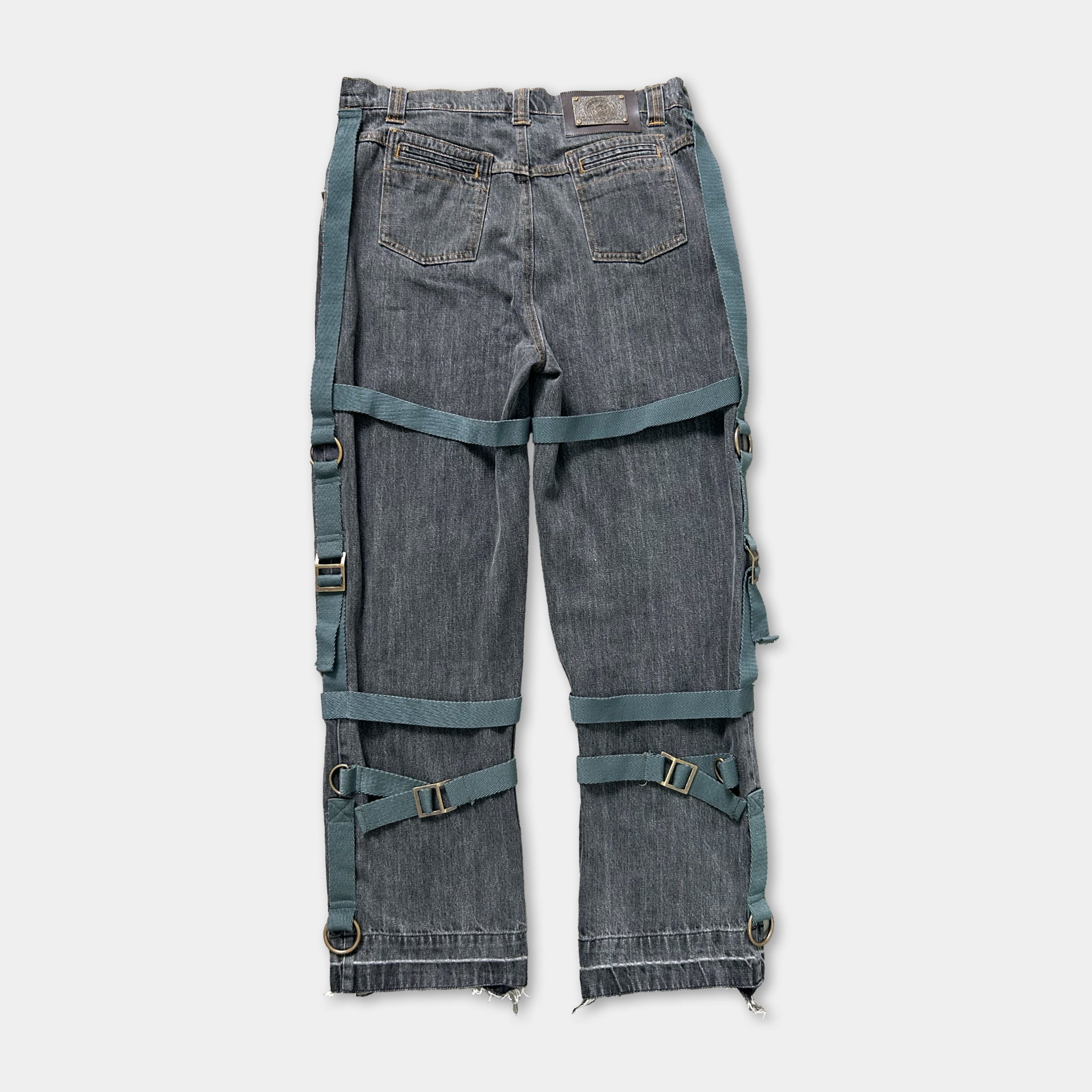 A pair of gray jeans with multiple straps and buckles attached to the waistband.