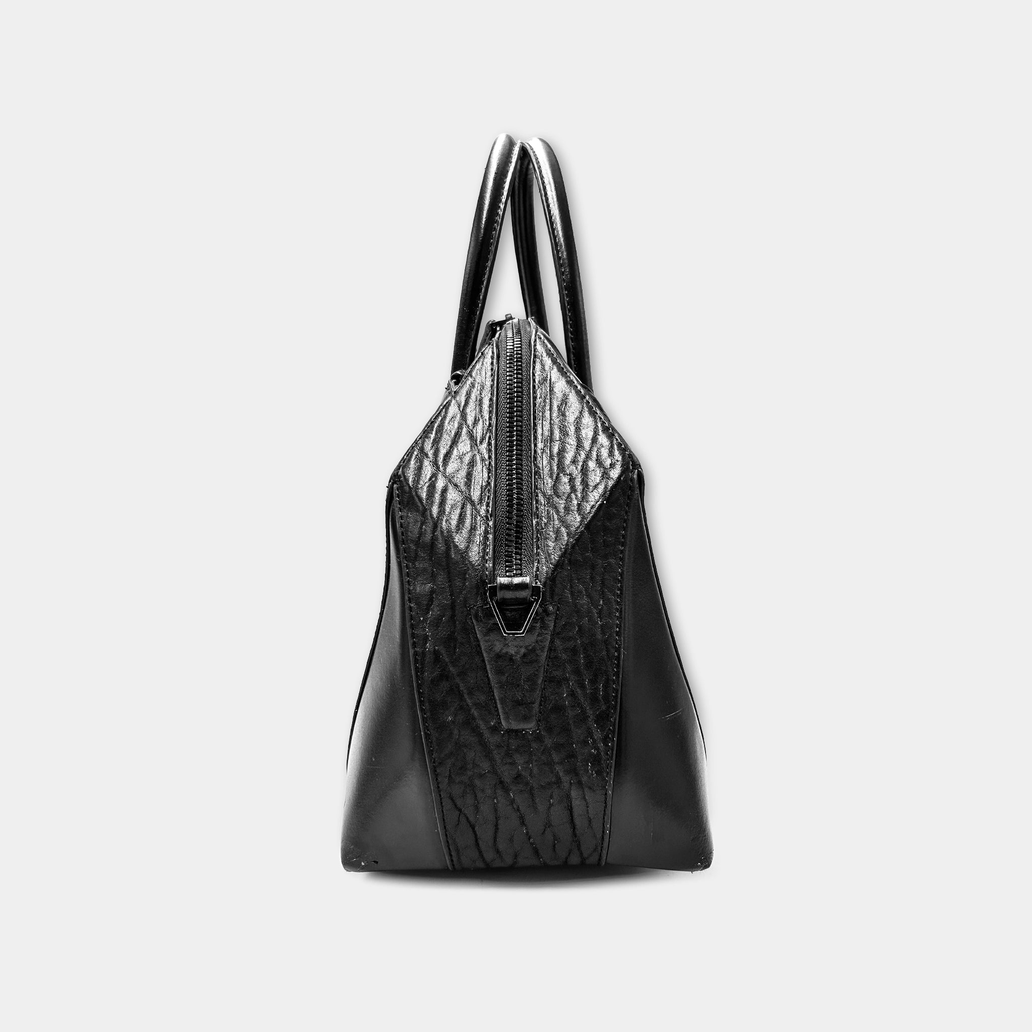 A black leather handbag with a distinctive zippered closure and two handles.