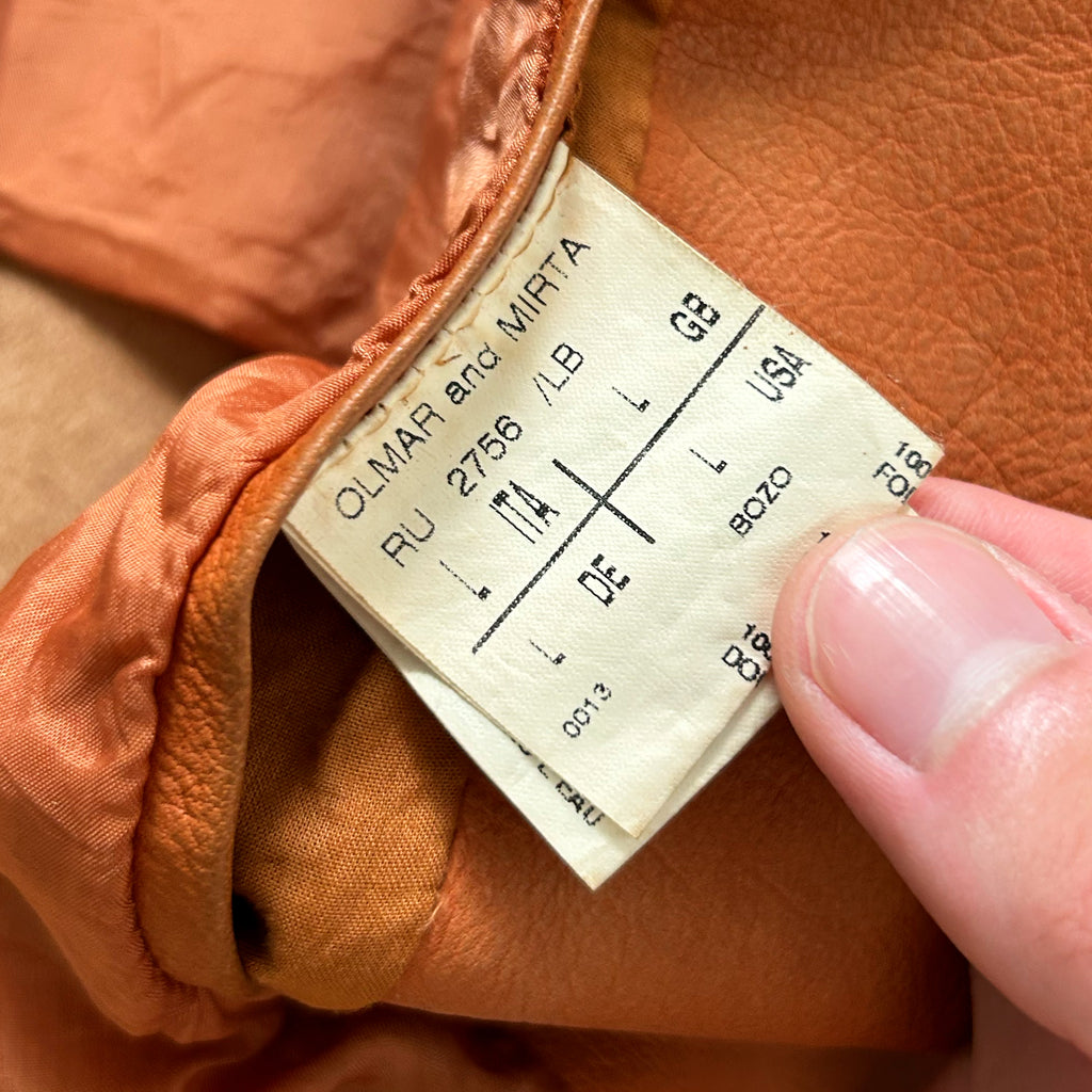 A close-up view of a label on a piece of clothing, with a person's hand holding it.