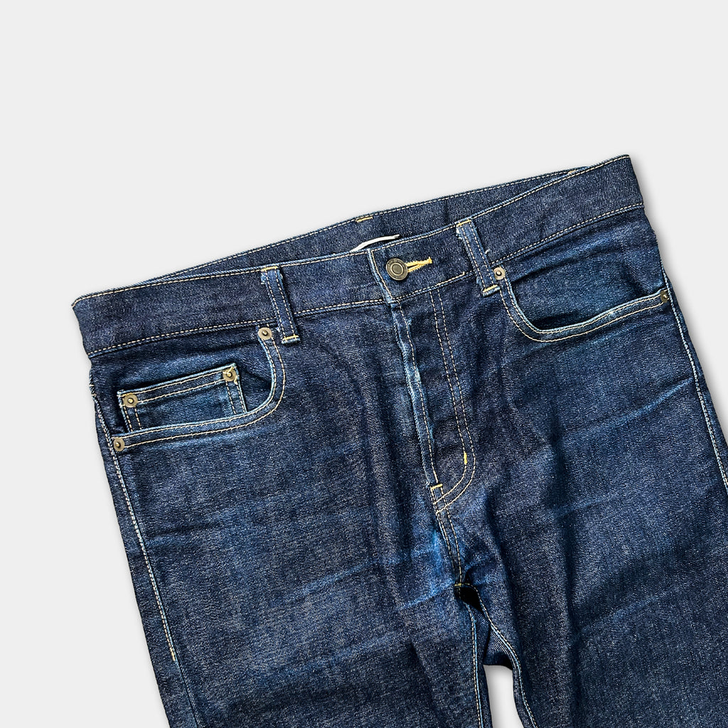 A pair of blue jeans with a zipper and pocket, displayed against a plain background.
