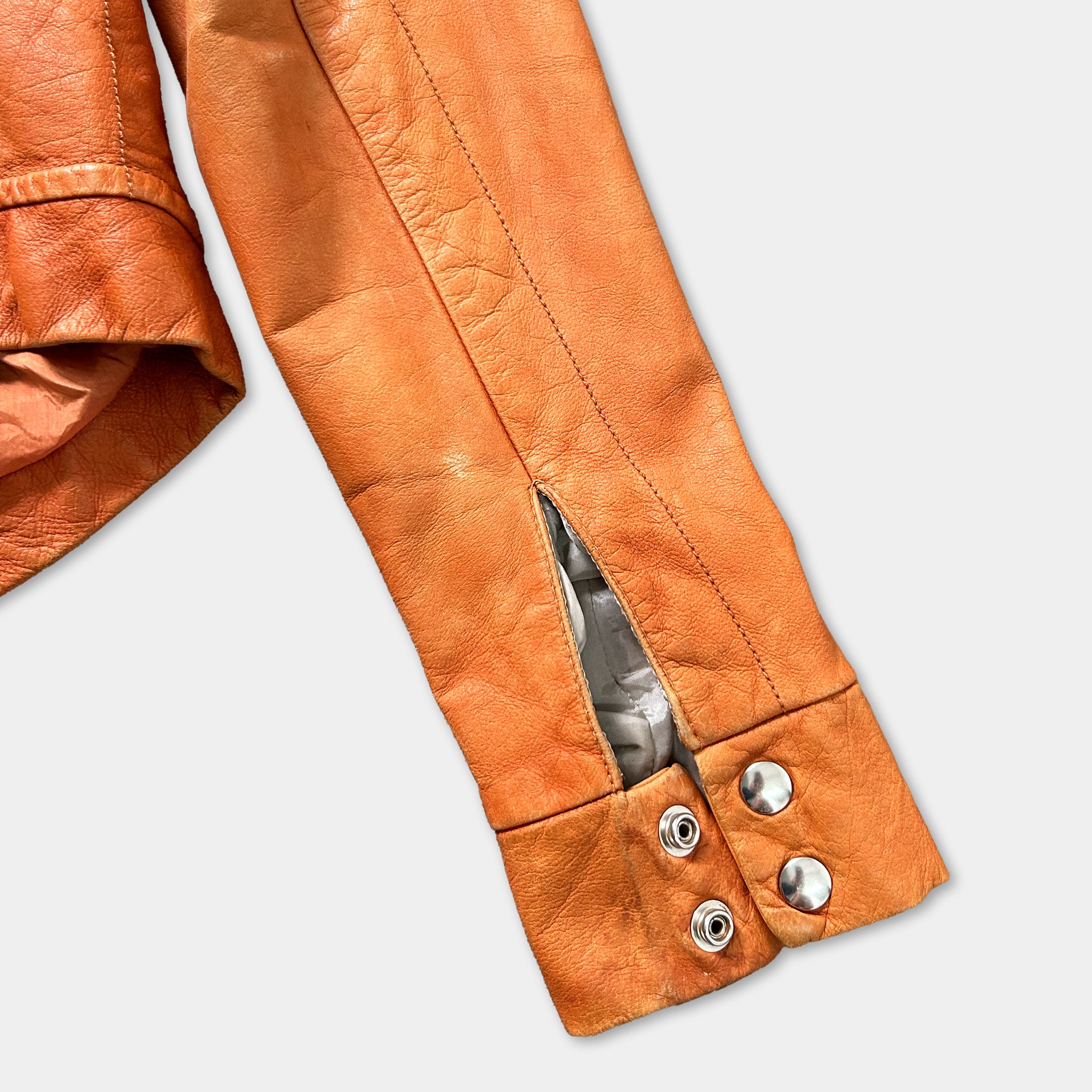 a close-up view of a brown leather jacket sleeve with a zipper and buttons.