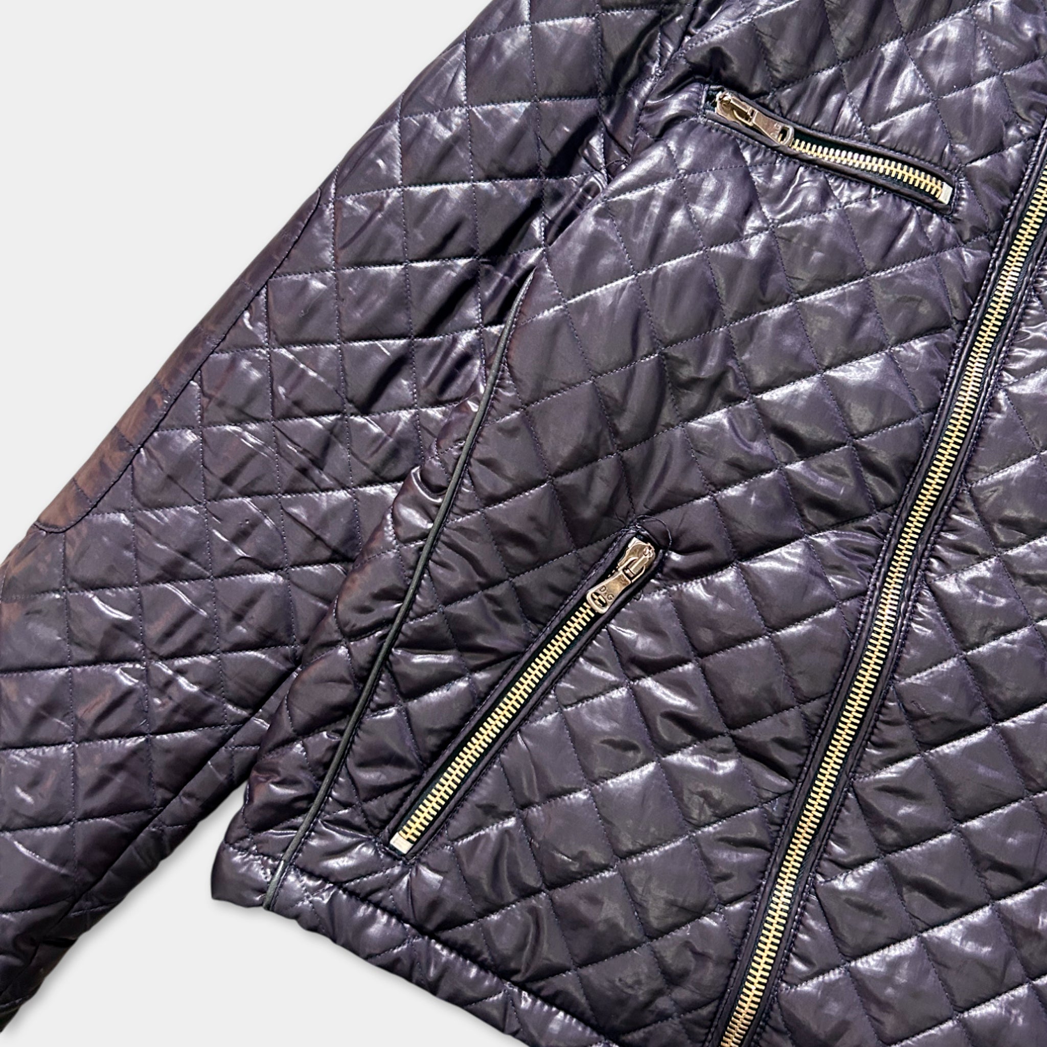 A close-up view of a black quilted jacket with gold zippers.