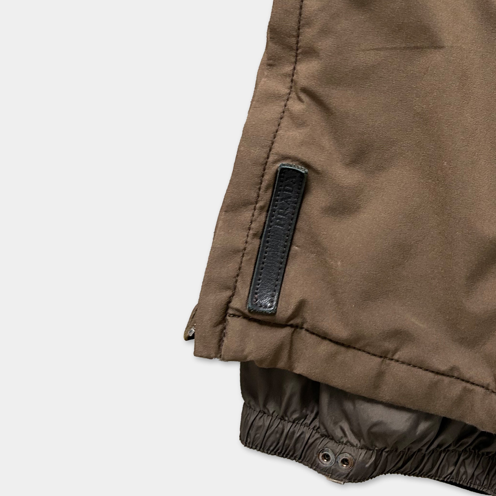 A close-up view of a brown jacket with a black zipper pull.