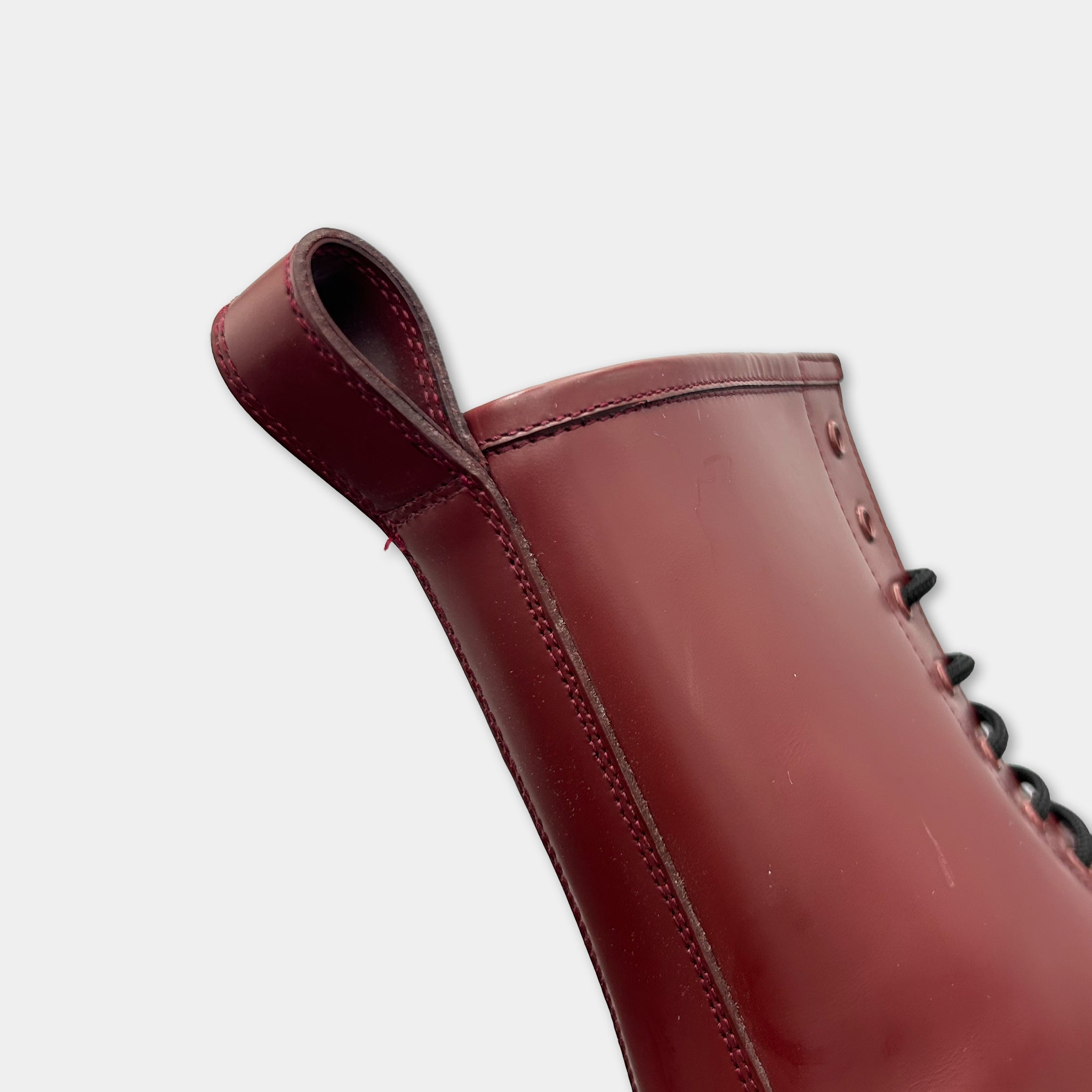 A close-up view of a red leather boot with a lace-up design.