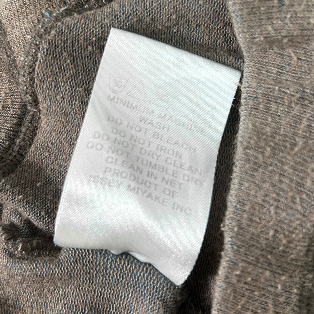 a close-up view of a white label attached to a piece of clothing, with text instructions on how to wash and care for the garment.