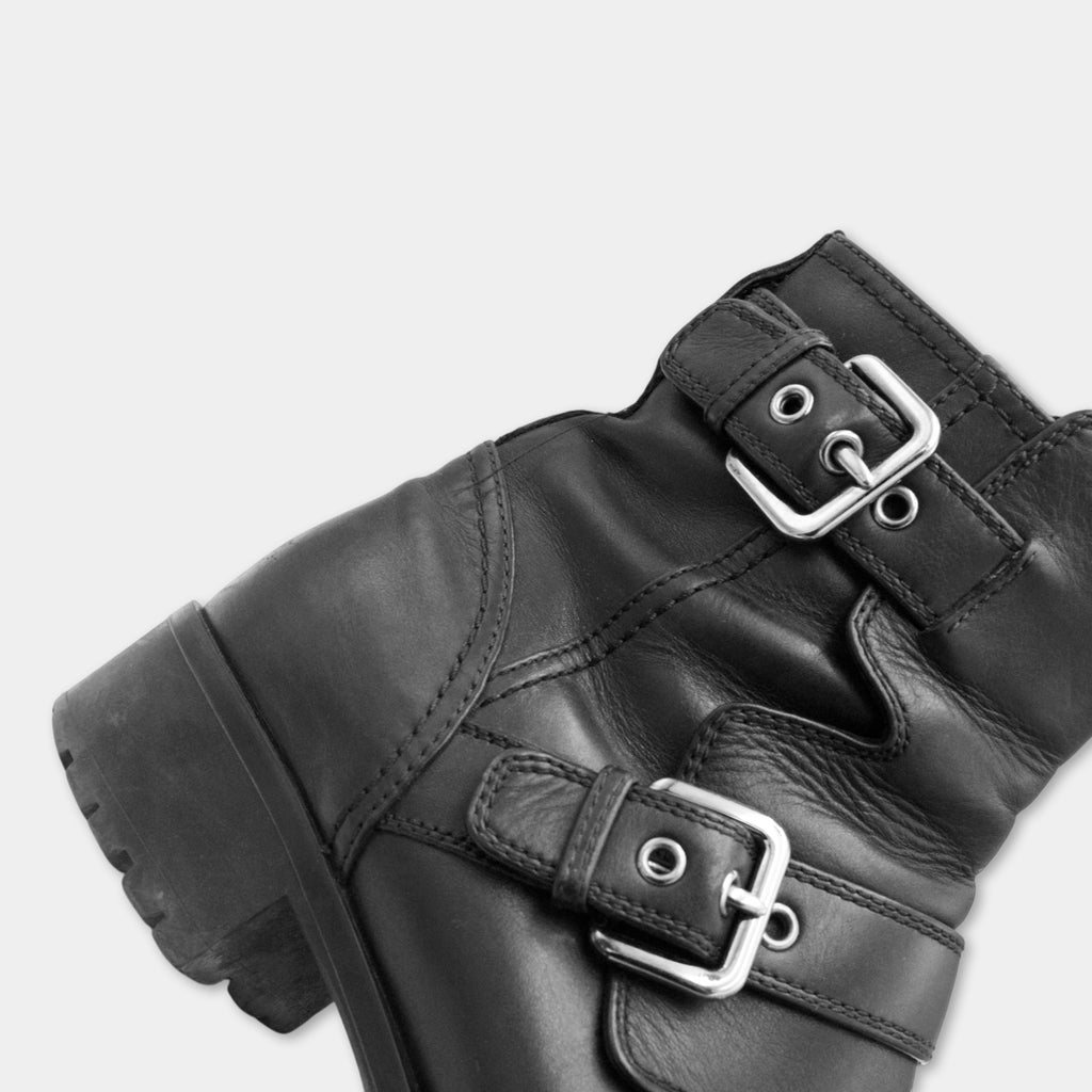 A close-up view of a black leather boot with metal buckles and straps.