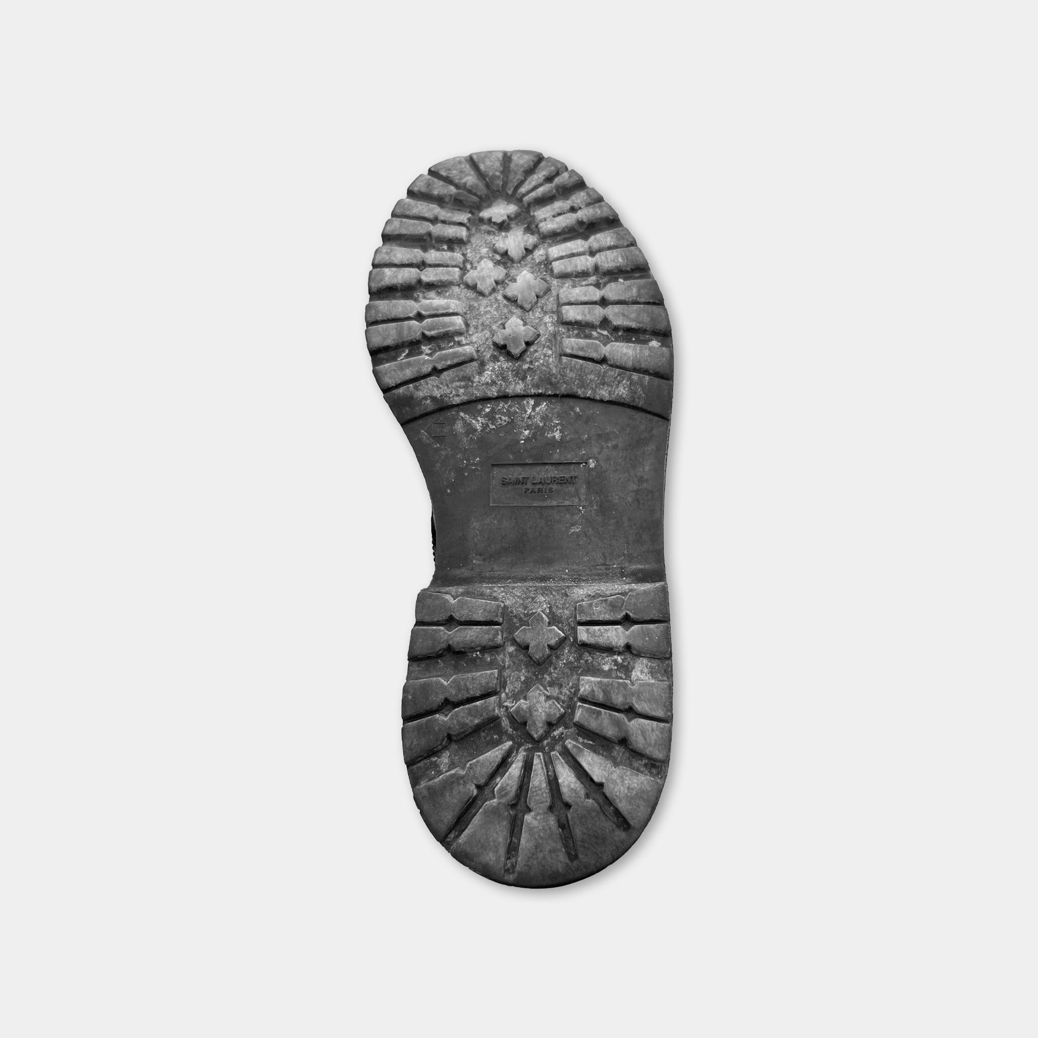 A close-up black and white image of a worn and dirty shoe sole.