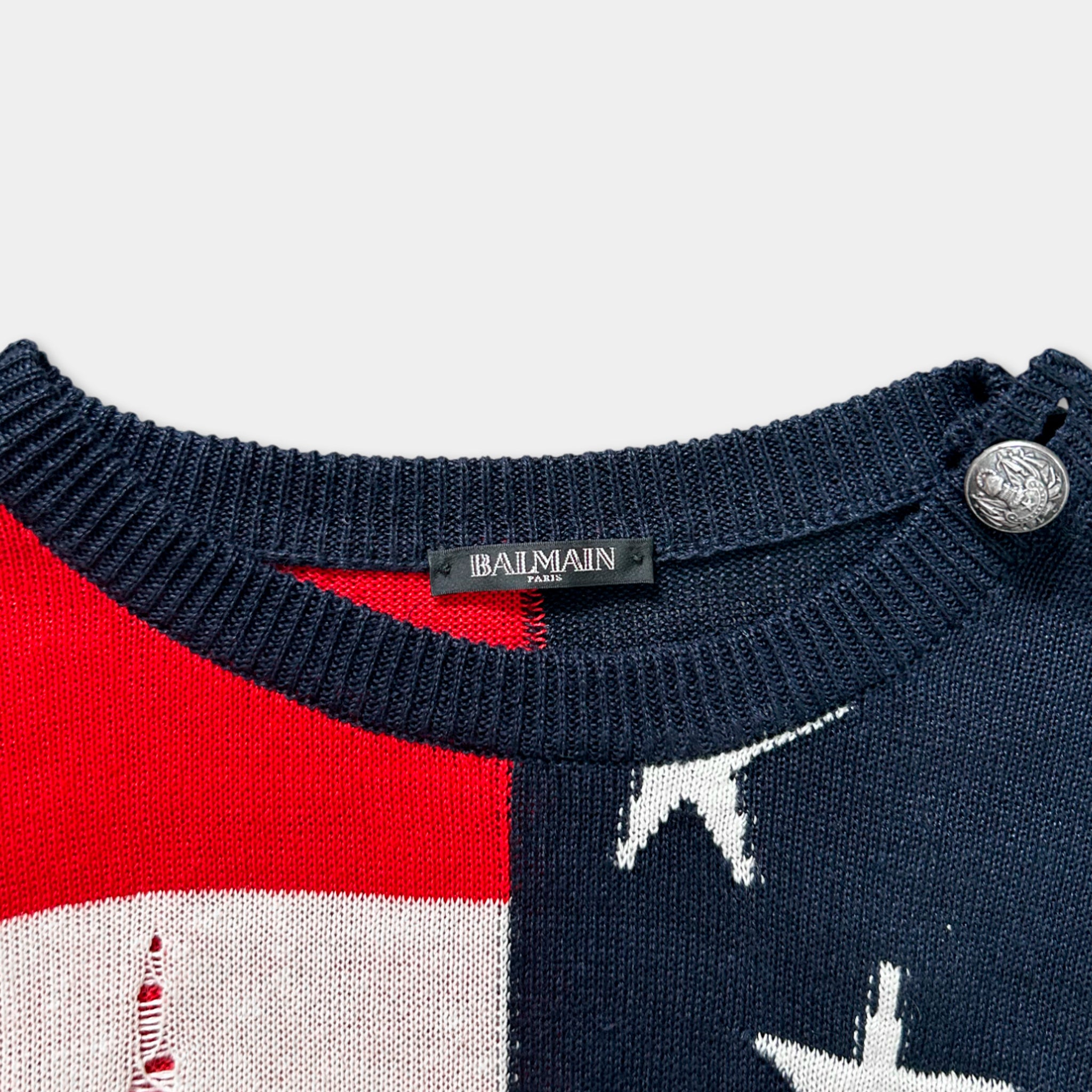 A close-up view of a navy blue sweater with a red and white pattern, featuring a label that reads "BAIMAIN" on the collar.