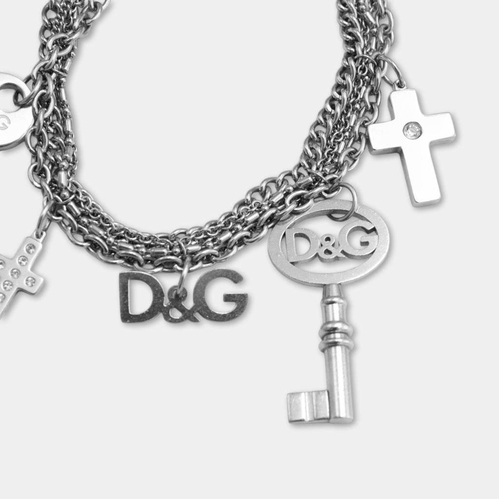 A silver-colored bracelet with various charms, including a cross, a key, and the letters 'D&G'.