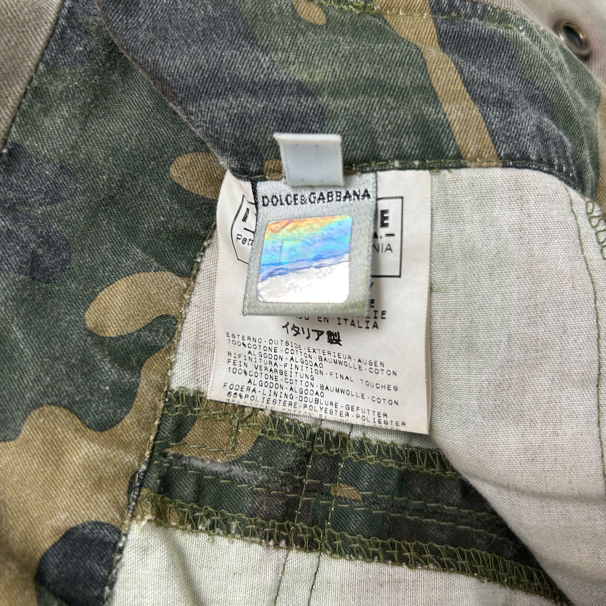 a close-up view of a label attached to a camouflage fabric, likely a piece of clothing or outdoor gear.